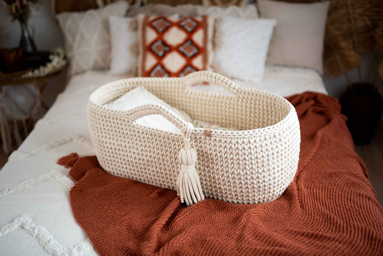 kosz mojżesza dla niemowląt stoi na łóżku